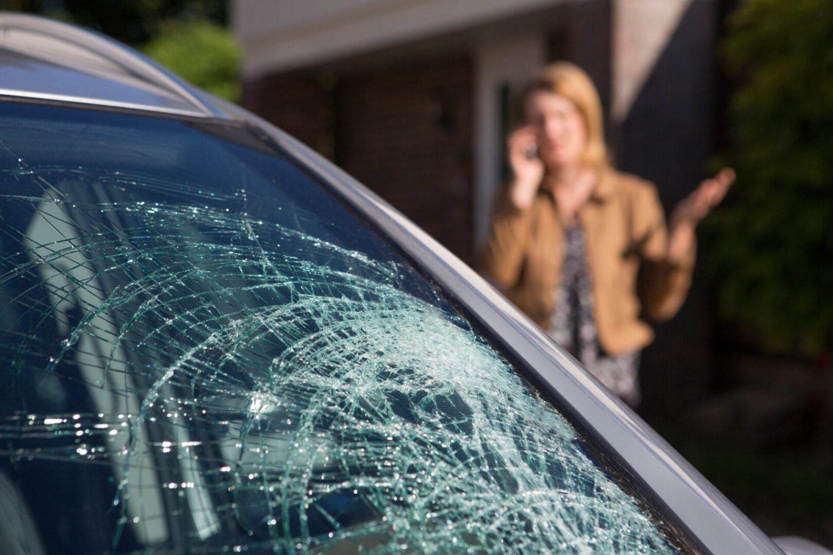 Ottawa driver on the phone beside a smashed windshield in her driveway